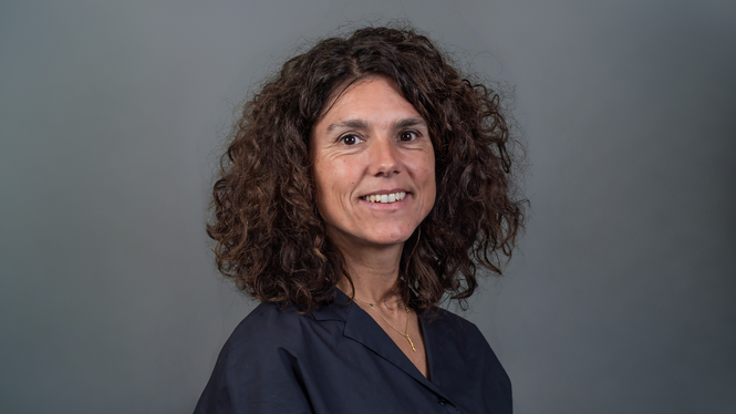 Home Porträt einer lächelnden Frau mit lockigem Haar vor grauem Hintergrund