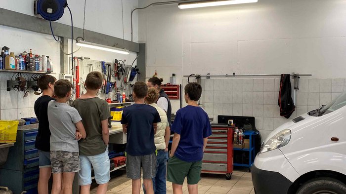 Mittelschule Dorf Tirol: Berufe praxisnah erleben Gruppe von Kindern in einer Autowerkstatt mit einer weißen Lieferwagen