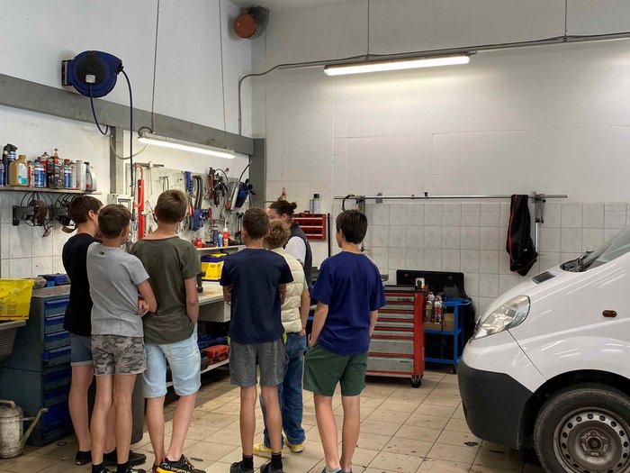 Mittelschule Dorf Tirol: Berufe praxisnah erleben Gruppe von Kindern in einer Autowerkstatt mit einer weißen Lieferwagen