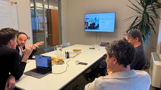 News Quattro persone in riunione in una sala conferenze con laptop e schermo