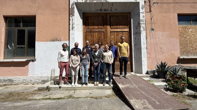Home Gruppe von zehn Personen vor einer großen Holztür an einem Gebäude