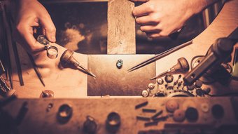 Home Juwelier untersucht blauen Edelstein mit Lupe auf Werkbank