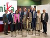 Home Gruppenfoto von zehn Personen mit fünf Statuen auf Podesten bei einer Veranstaltung