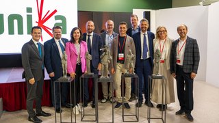 News Gruppenfoto von zehn Personen mit fünf Statuen auf Podesten bei einer Veranstaltung