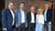 Home Fünf Personen stehen vor einer dunklen Holzwand für ein Gruppenfoto