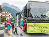 Home Familie steigt in grünen Bus in bergiger Stadt mit traditionellen Häusern ein