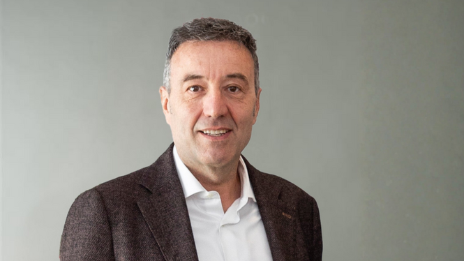 Home Porträt eines lächelnden Mannes in weißem Hemd und dunklem Sakko vor grauem Hintergrund