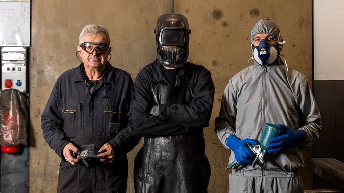 Handwerk hautnah erleben: Schülerinnen und Schüler erkunden vielfältige Berufe und Betriebe im Eggental Drei Arbeiter in verschiedenen Schutzkleidungen vor einer Wand in einer Werkstatt