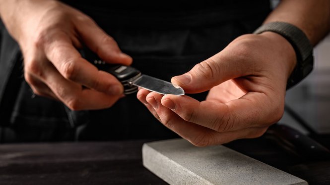 Home Mann schärft Klappmesser an Schleifstein