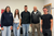 Home Fünf lächelnde Personen stehen für ein Gruppenfoto in einem Innenraum zusammen