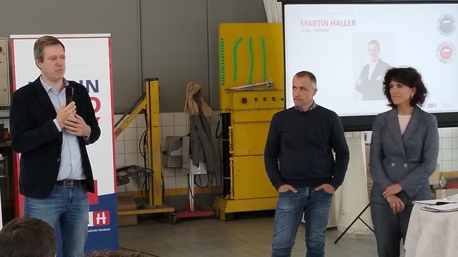 Home Drei Personen bei einer Präsentation in einer Werkstatt mit Publikumsbeteiligung