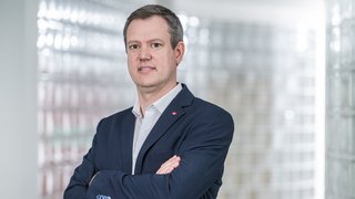 News Geschäftsmann in Anzug steht mit verschränkten Armen vor glasigem Hintergrund