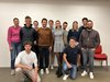 Home Gruppe von zwölf lächelnden jungen Erwachsenen vor weißer Wand