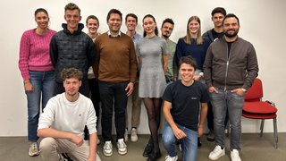 News Gruppo di dodici giovani adulti sorridenti davanti a parete bianca