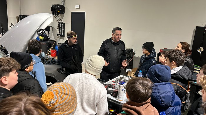 Tag des Kachelofens am 20. Oktober Gruppe von Jugendlichen hört einer Erklärung in einer Autowerkstatt zu