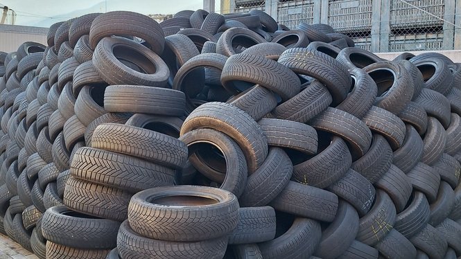 Home Ein großer Haufen alter Autoreifen vor einem Industriegebäude