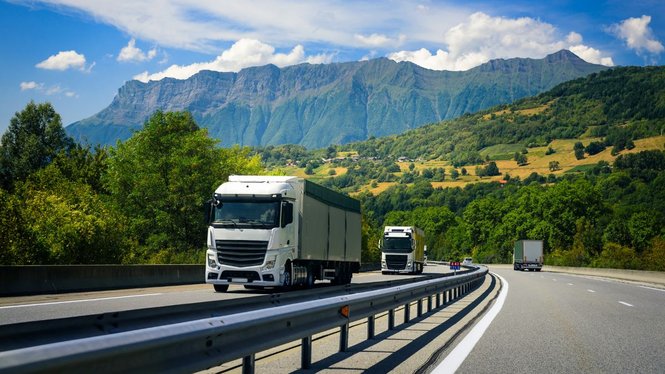 Home Lastwagen auf einer Autobahn vor einer grünen Berglandschaft