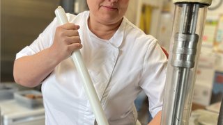 News Donna in giacca da cucina bianca mescola con bastone grande in contenitore metallico