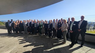 News Große Gruppe von Menschen, die vor Glasgeländer und klarem Himmel stehen