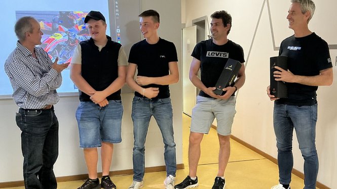 Home Fünf Männer stehen vor einer Präsentation, zwei halten schwarze Boxen
