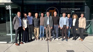 News Gruppe von elf Personen vor einem Gebäude mit der Nummer 18