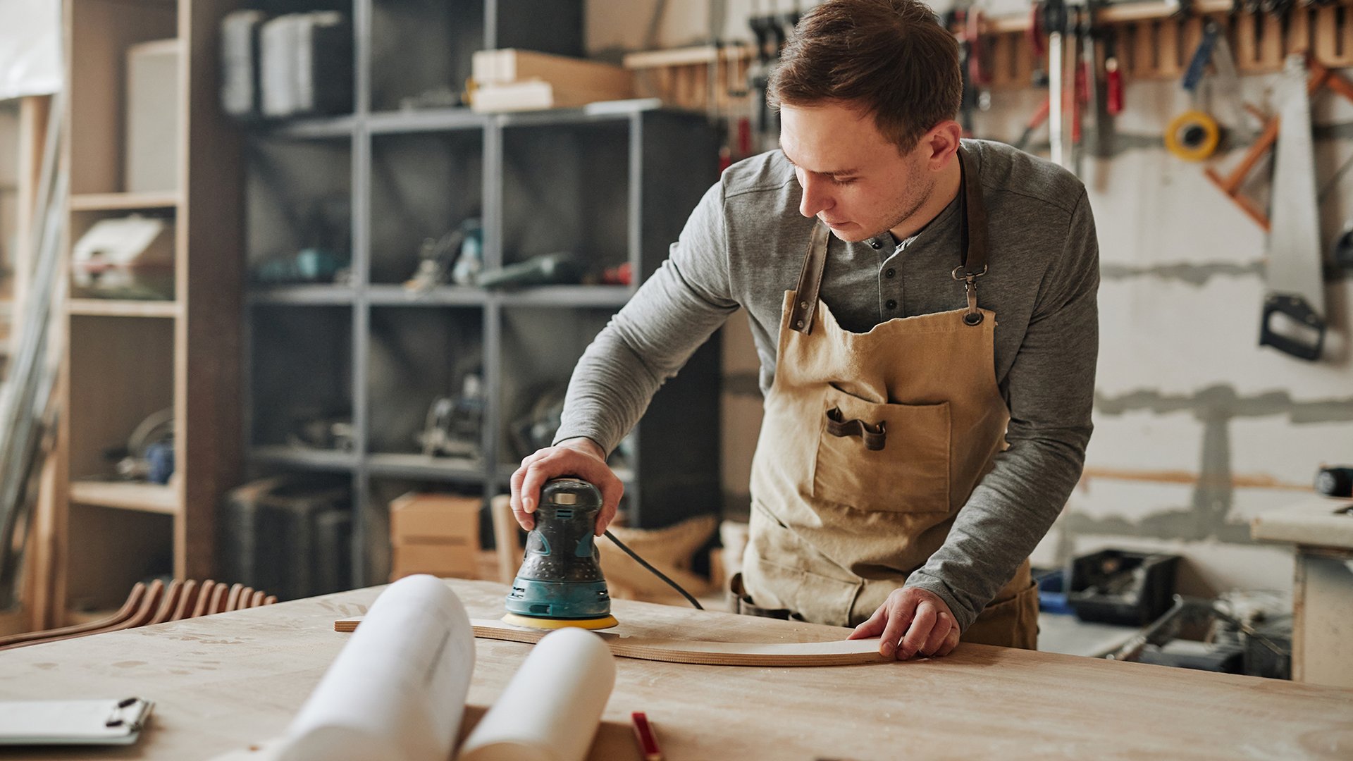 Home Mann schmirgelt Holzbrett in einer Werkstatt
