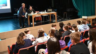 News Zwei Frauen sprechen vor einem Publikum von Jugendlichen in einem Theater