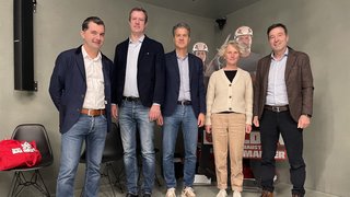 News Fünf Personen stehen in einem Raum vor einer Baustellenwerbung