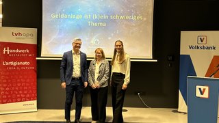 News Tre persone davanti a schermo con presentazione su investimenti e striscioni bancari