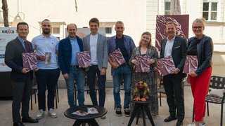 News Gruppo di otto persone con brochure durante un evento in cortile interno