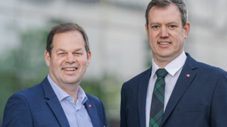 News Due uomini in abiti sorridono con sfondo sfocato