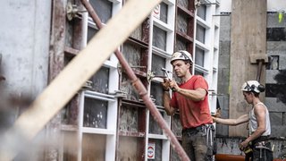 News Due operai con caschi lavorano a una parete di cemento in un cantiere edile