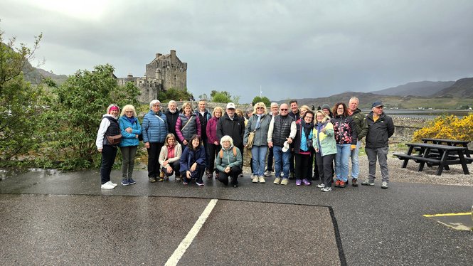 Home Gruppenfoto von 25 Personen vor einer alten Burg in einer bergigen Landschaft