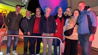 News Foto di gruppo di otto persone in un osservatorio con un grande telescopio