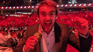 News Mann jubelt mit Goldmedaille auf großer Veranstaltung vor rotem Publikum