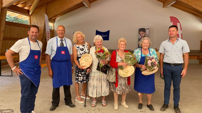 L’orgoglio degli Artigiani Anziani in scena a Verano Gruppo di persone in una struttura di legno con fiori e premi in legno