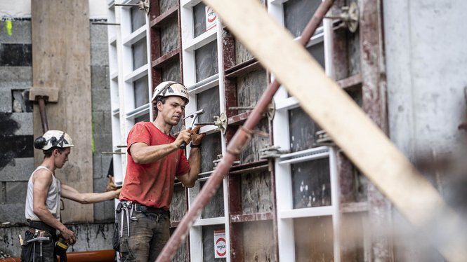 Home Zwei Bauarbeiter mit Helmen montieren Schalungen auf einer Baustelle