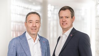 News Due uomini in giacca e camicia davanti a uno sfondo chiaro sfocato