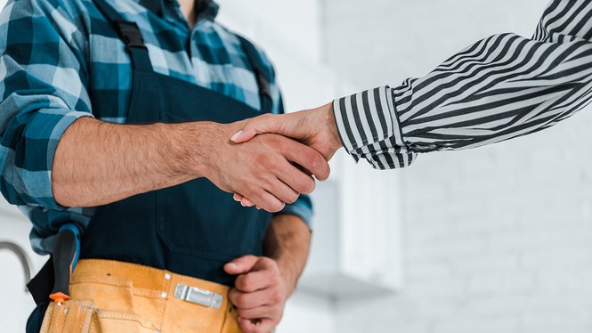 Home Handschlag zwischen Handwerker mit Werkzeuggürtel und Person im gestreiften Hemd