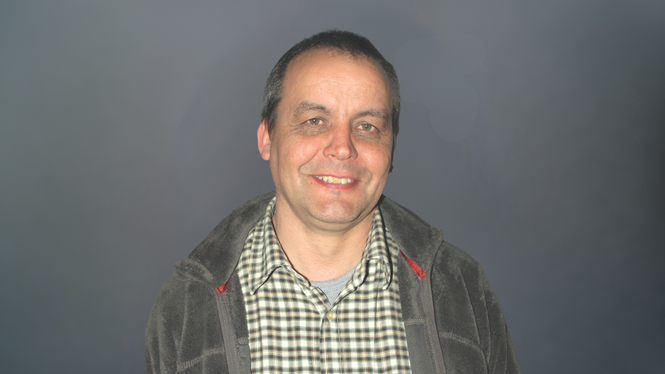 Home Mittelalter Mann mit kariertem Hemd und Jacke vor grauem Hintergrund lächelnd