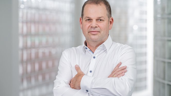 Home Porträt eines Mannes mit weißem Hemd und verschränkten Armen in hellem Raum