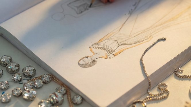 Home Hand zeichnet Modedesign in Skizzenbuch mit Schmuck im Vordergrund