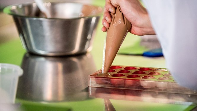 Home Hand füllt Pralinenform mit flüssiger Schokolade