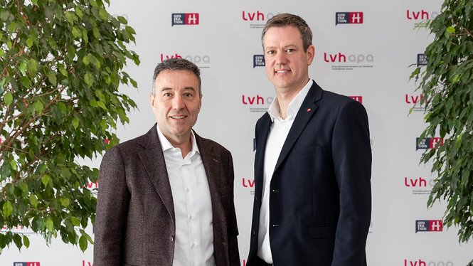 Home Zwei Männer in Anzügen vor LVHapa und Generation H Banner mit Pflanzen