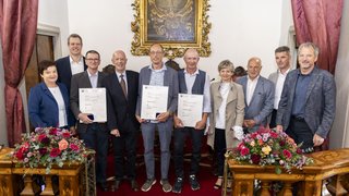 News Gruppe von Menschen in feierlicher Umgebung mit Blumen und Urkunden