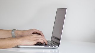 News Hände tippen auf Laptop-Tastatur auf weißem Schreibtisch mit Pflanze