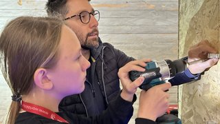 News Frau lernt vom Mann Bedienung eines Akkuschraubers bei Elektriker-Training