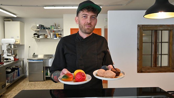 Home Koch hält zwei Teller mit bunten Pralinen in einer Küche