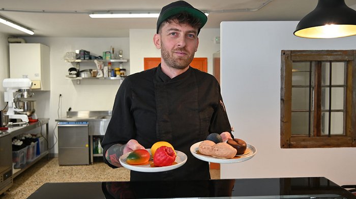 Giovani artigiani (lvh.apa) e giovani albergatori (HGJ) in visita alla Scuola media del convento delle Orsoline a Brunico Cuoco che tiene due piatti con cioccolatini colorati in cucina