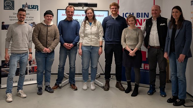 Home Gruppe von acht Personen steht vor Bannern und lächelt in die Kamera